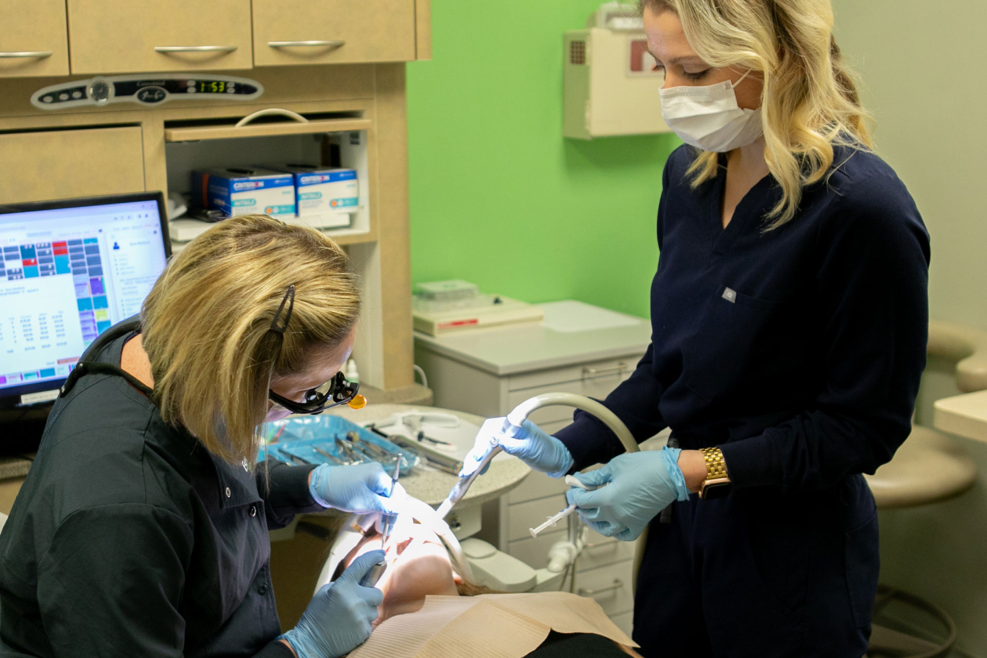dentist and assistant performing oral exam on patient