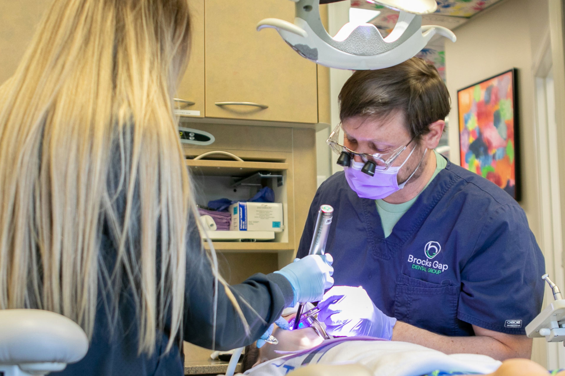 Dr. Johnson and assistant performing oral exam on patient